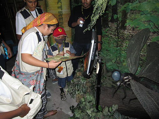 Nik Alik Irfan ( centre ) completes the scavenger hunt with the help of a GIS student at the gigantic pre-historic dragonfly exhibit at Dinoscovery by Dinosaurs Live!